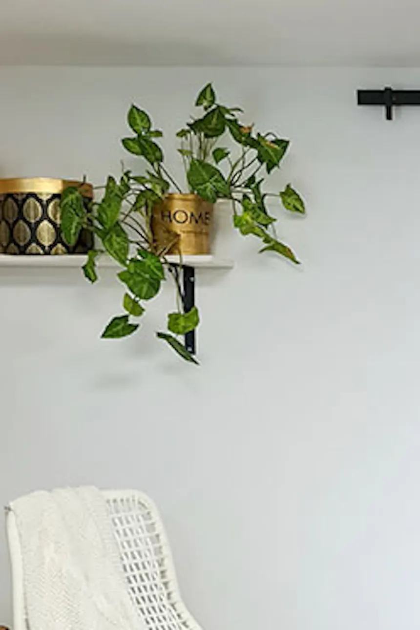 round, braided jute rug, white rocking chair with decorative pillow, wooden sliding door in the entrance to the bedroom, white walls in a Scandinavian interior, white bed in the bedroom