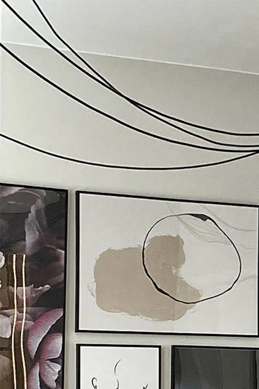 Gallery of posters on a gray wall with industrial pendant lights in a small bedroom