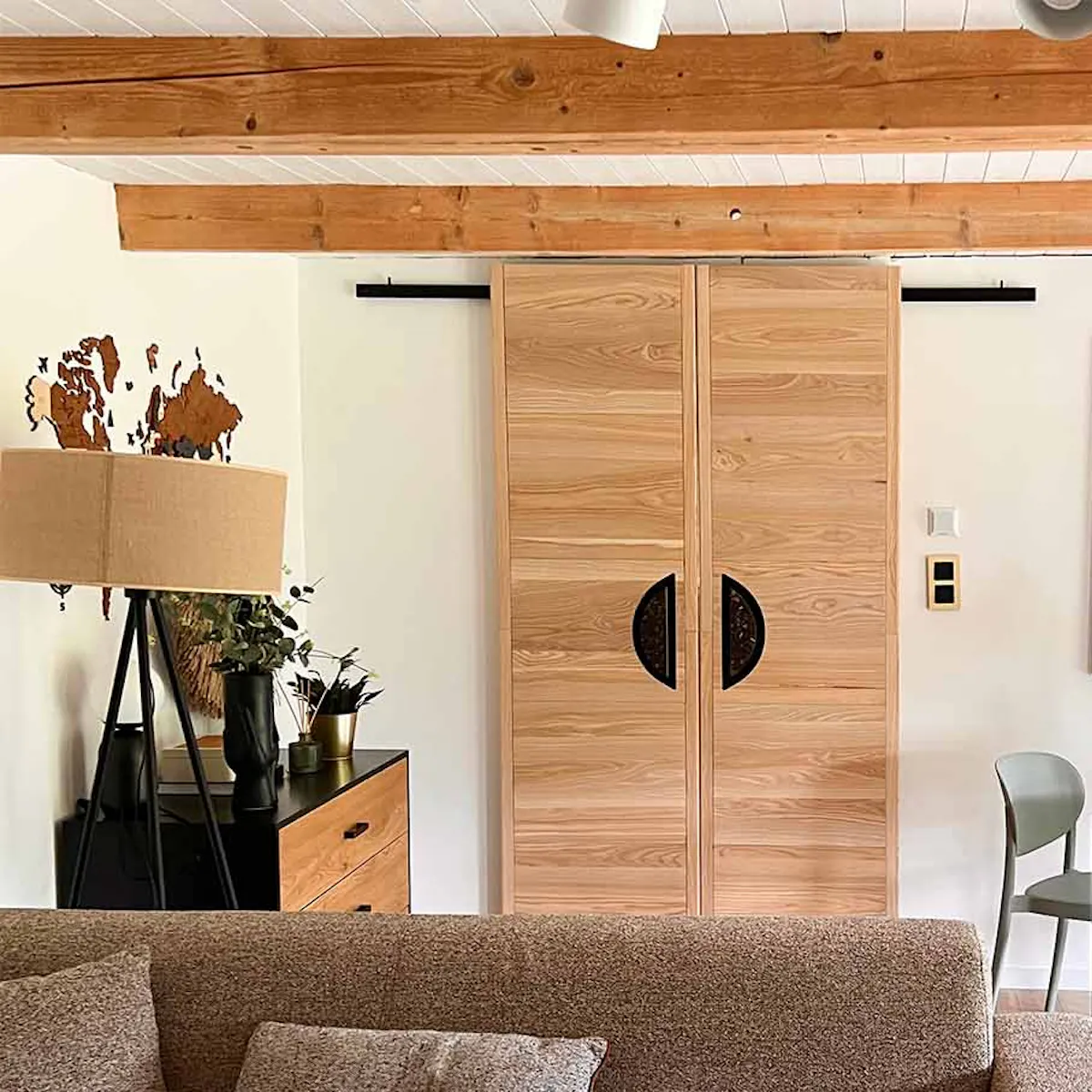 a grey and brown sofa and double wooden sliding doors in a living room decorated in earth tones