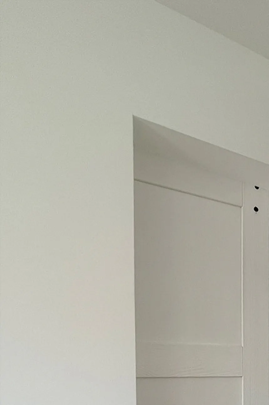 Modern white sliding wood doors against white wall in bedroom