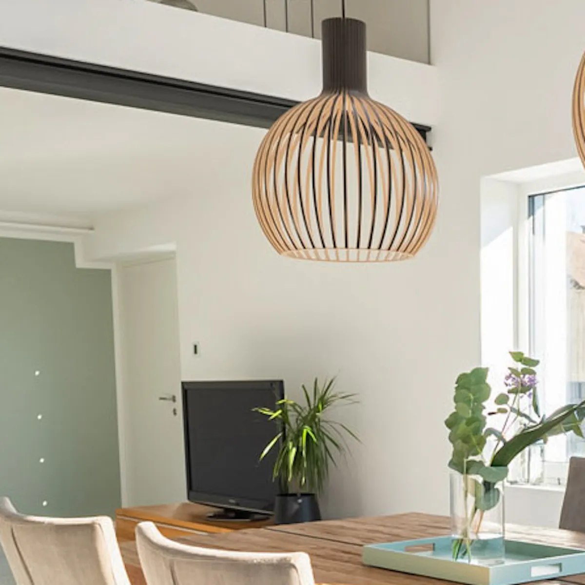 Solid wood dining table, beige upholstered chairs, perforated pendant lights above dining table, modern living room