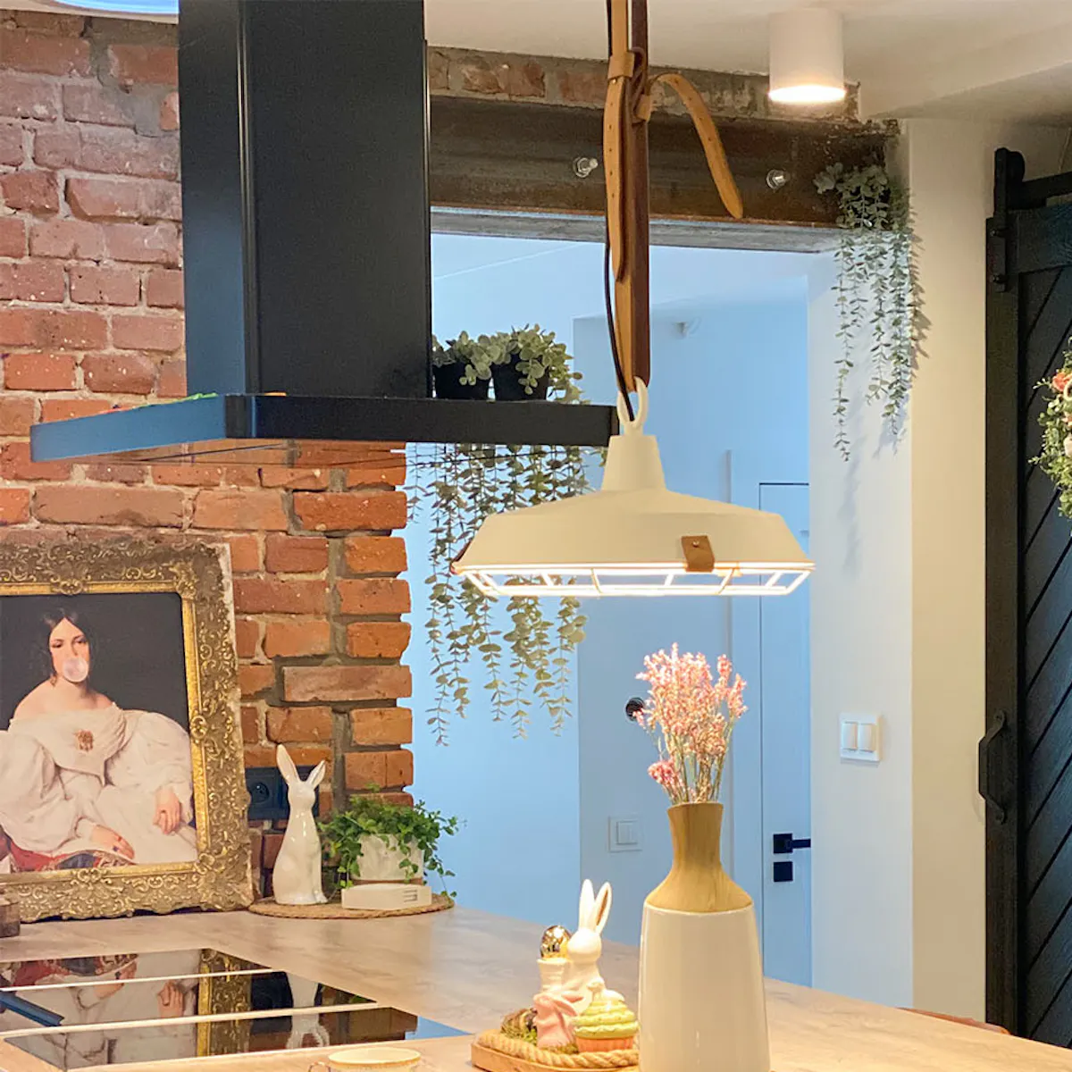 Large kitchen island with wooden top, black hood above kitchen island, sliding door to pantry, decorative wreath on door