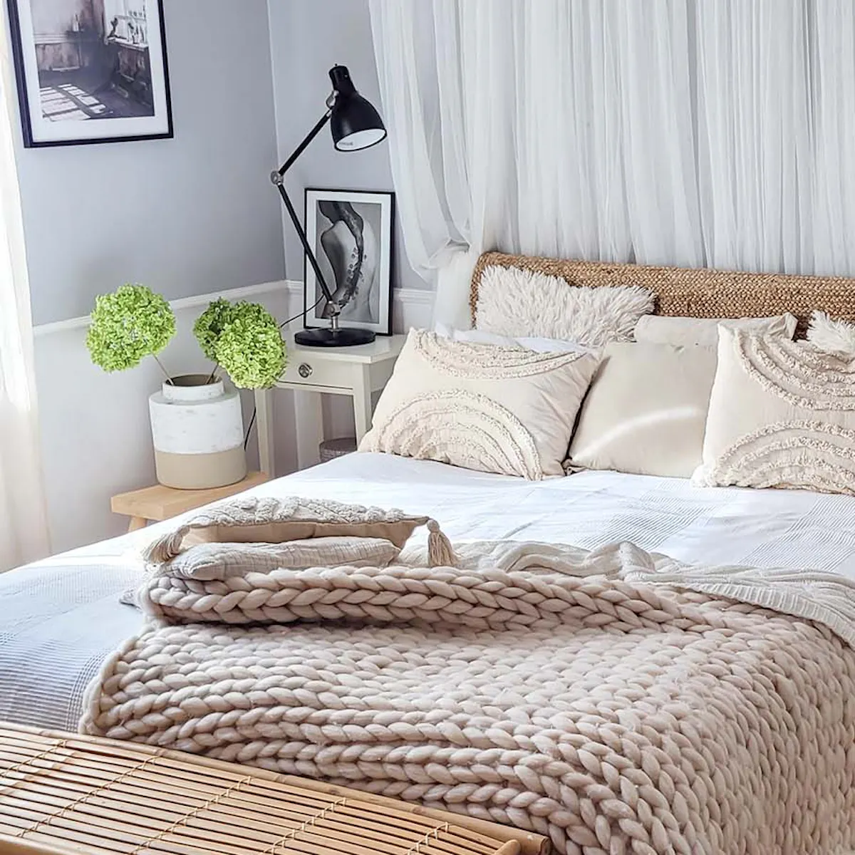 un lit double recouvert d'une literie blanche, d'une couverture épaisse et de coussins décoratifs