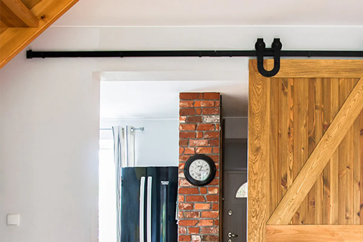 rustic wooden door, brushed wood sliding door, barn door, sliding door with a horseshoe, large blue sofa in the living room, sliding door to the kitchen
