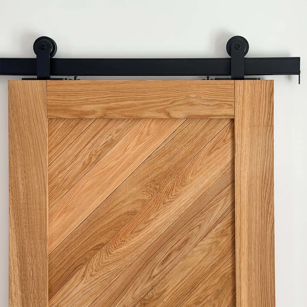Gros plan sur le veinage naturel de la porte coulissante en chêne CARO montée sur le système noir Smart.