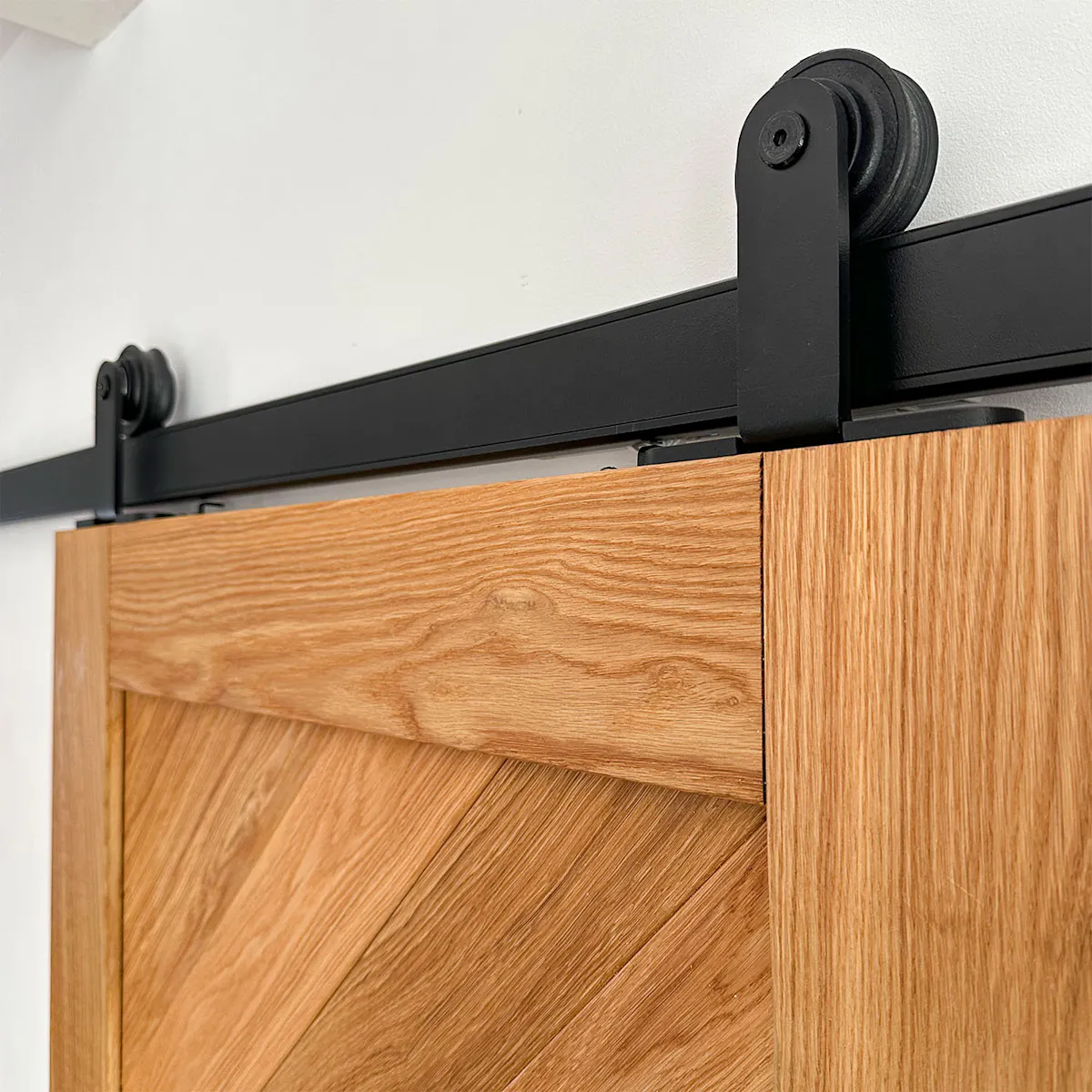 Close-up of the black Smart sliding system mounted on a CARO oak door.