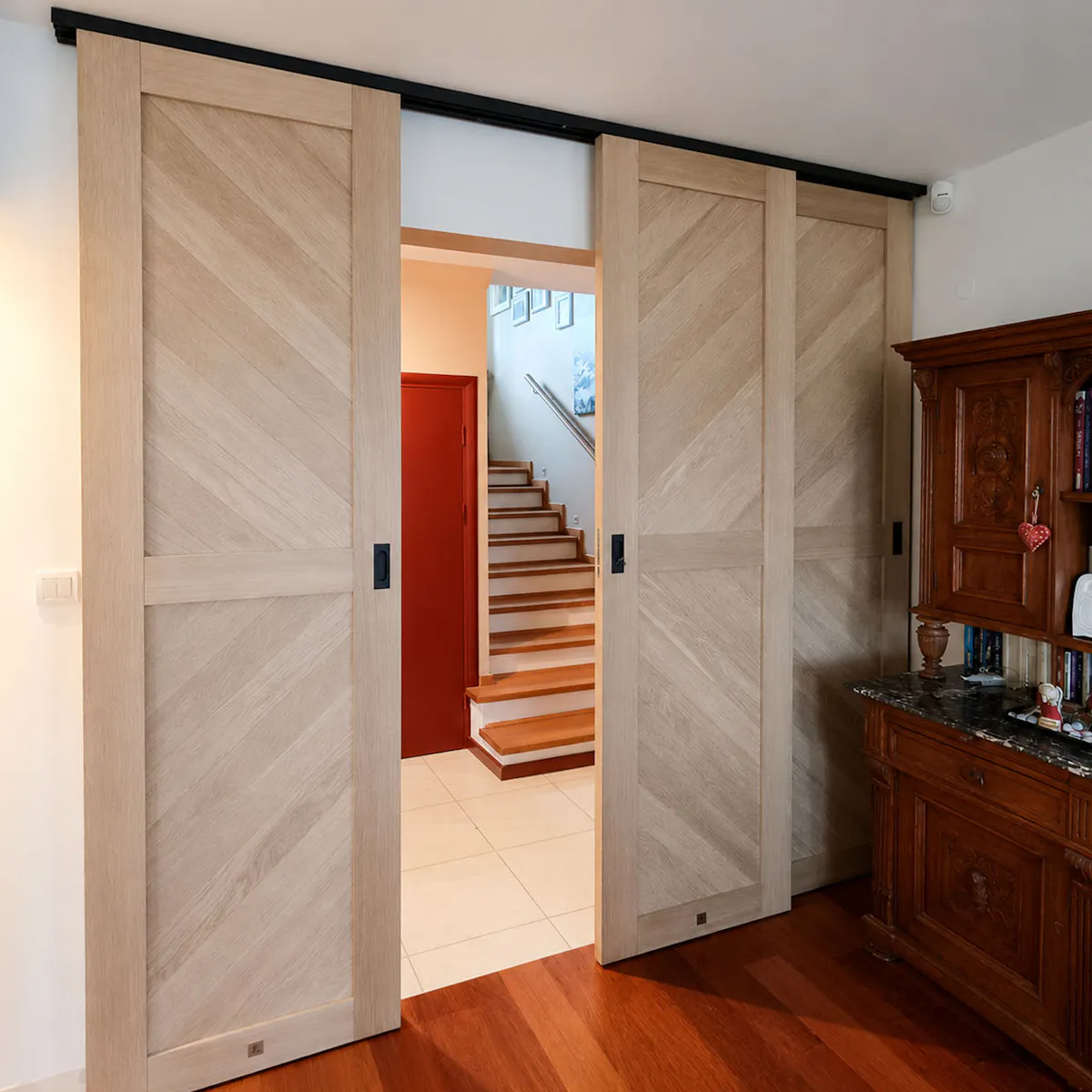 Four-panel bypass sliding doors open with panels overlapping to reveal hallway with staircase
