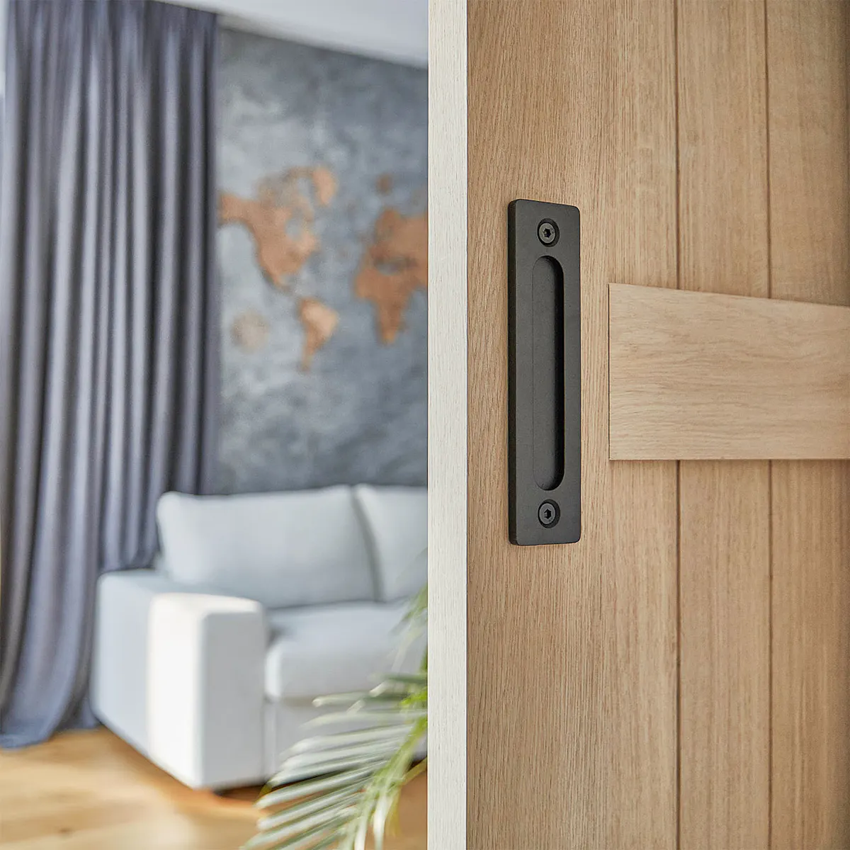 porte en bois entrouverte révélant une partie d'une pièce avec un canapé gris et des murs gris
