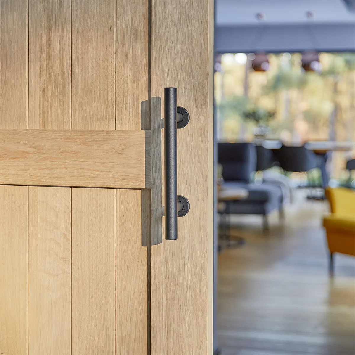 poignée de porte noire sur une porte en bois en chêne naturel