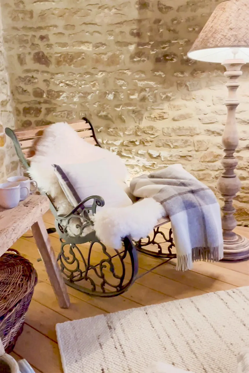 une chaise à bascule recouverte de couvertures moelleuses à côté d'un lampadaire avec un grand abat-jour