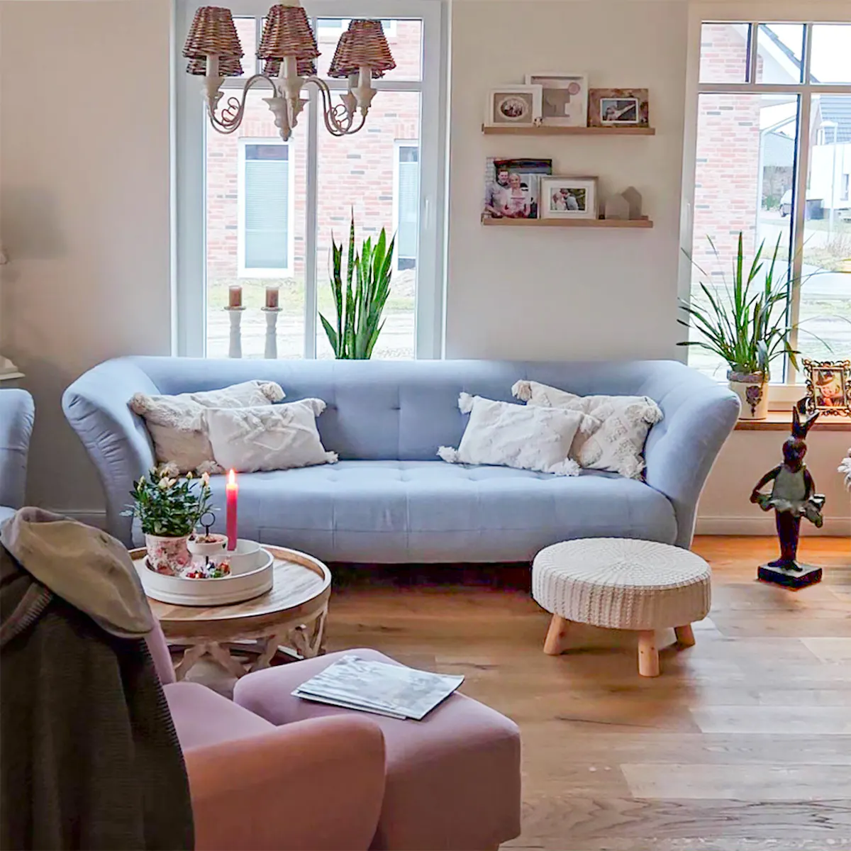 Living room with light blue sofa, white pillows, wood coffee table, and woven pouf