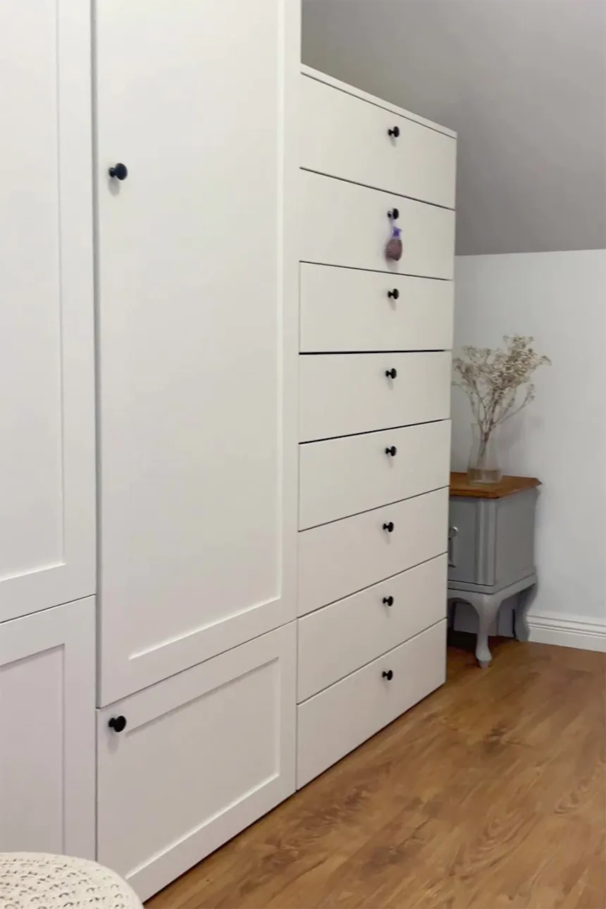 armoires et commodes blanches sous plafond mansardé dans le dressing