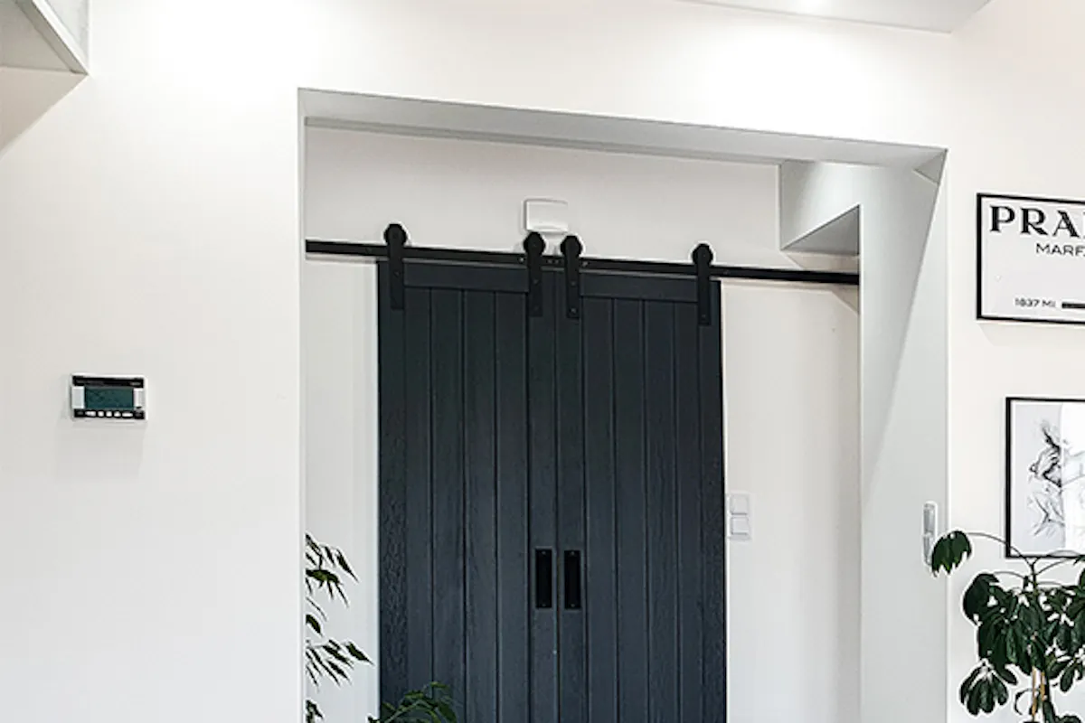 Entryway of modern home with double sliding doors, poster gallery, and openwork chairs