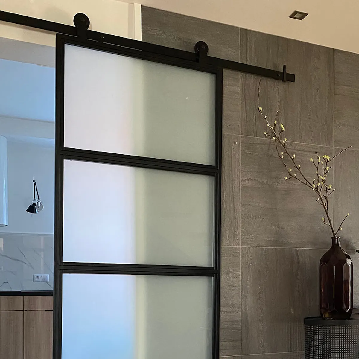 Loft glass doors, metal glass door for kitchen, bright kitchen with cooking island, graphite wall tiles, black decorative console with mirror in hallway, wicker basket with pillows