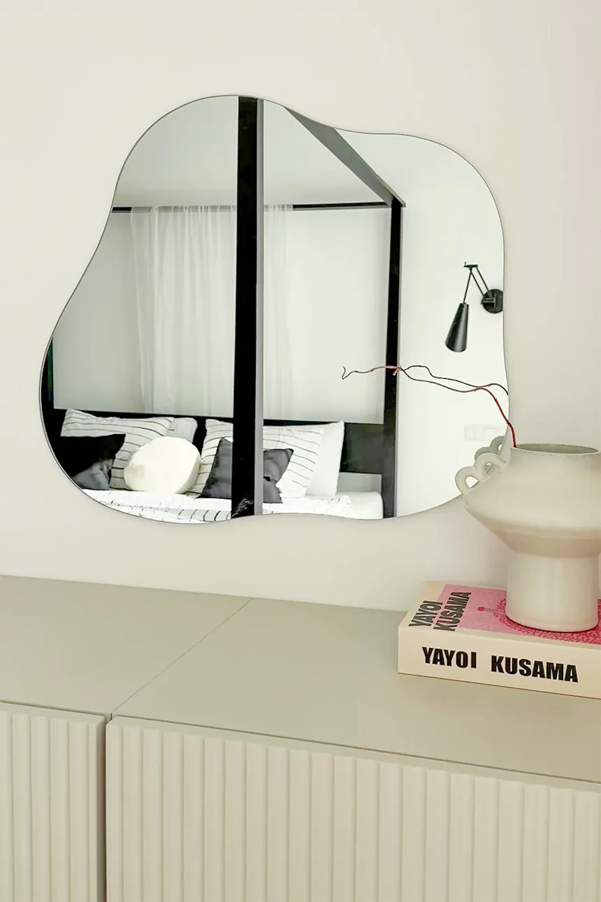 Modern wall mirror with irregular, organic shape in minimalist interior