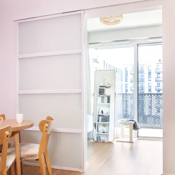 Open white sliding doors with frosted glass revealing bright room with standing mirror and cat scratching post