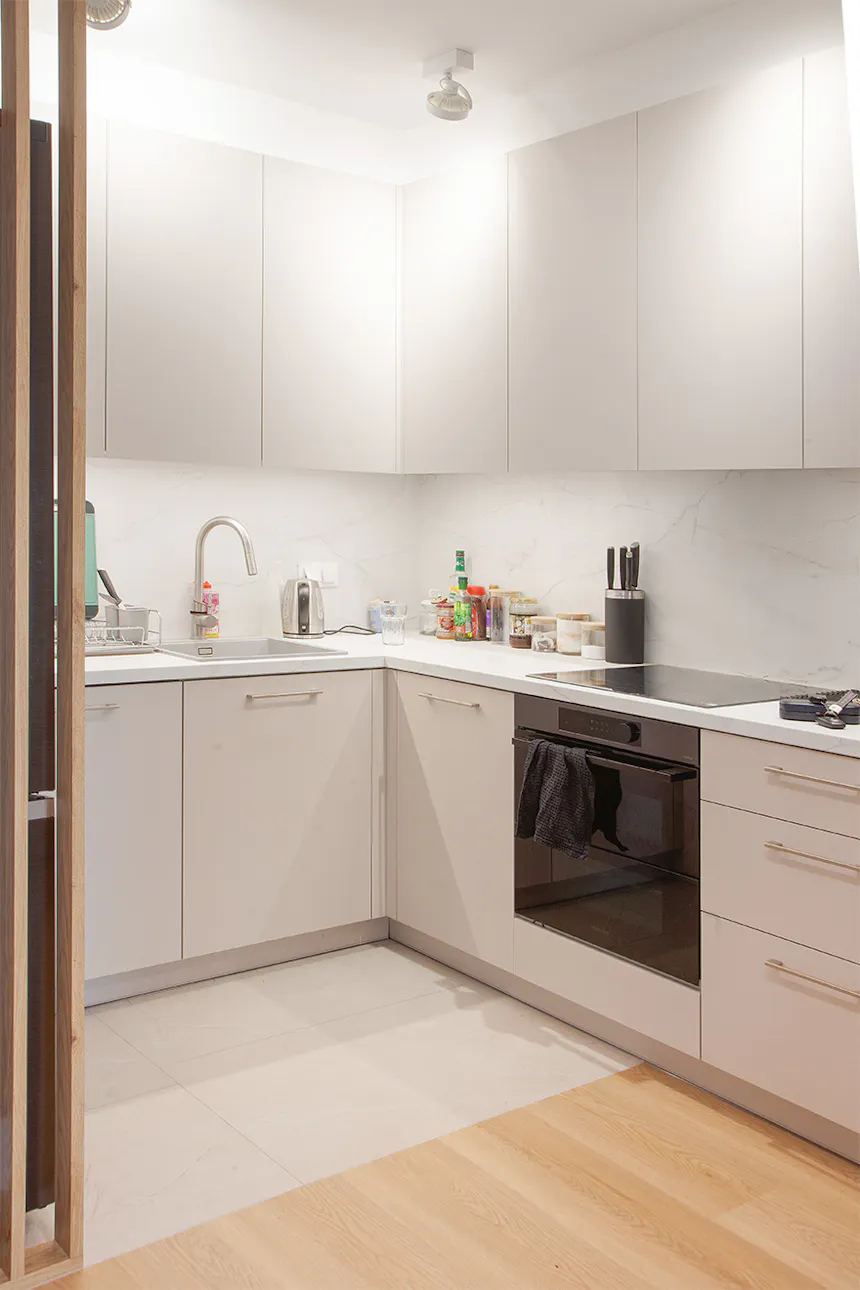Cuisine moderne et lumineuse avec des armoires gris clair et un comptoir blanc.
