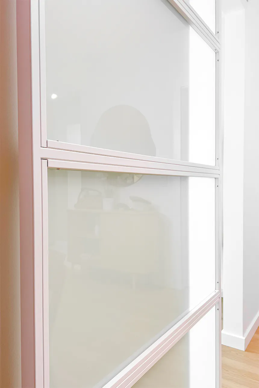 Gros plan sur une porte coulissante blanche avec quatre panneaux en verre dépoli, montrant sa construction.