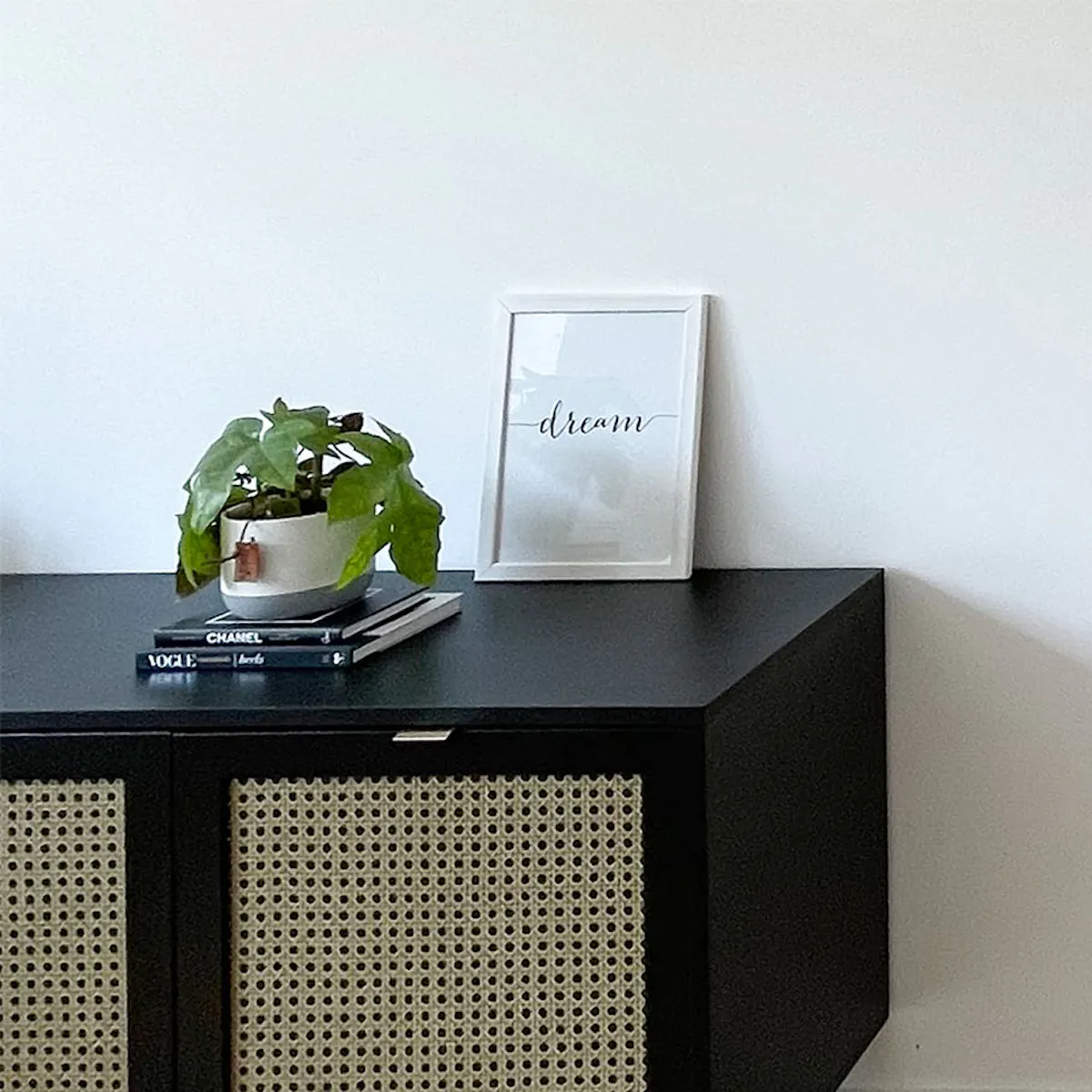 Black low rattan dresser against white wall