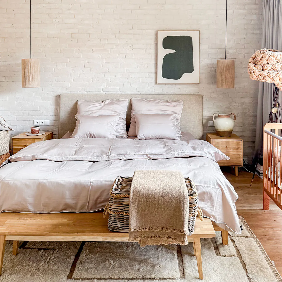 A minimalist-style beige bedroom featuring an oak-framed bed, a white brick wall and linen lamps. A harmonious interior that encourages relaxation.