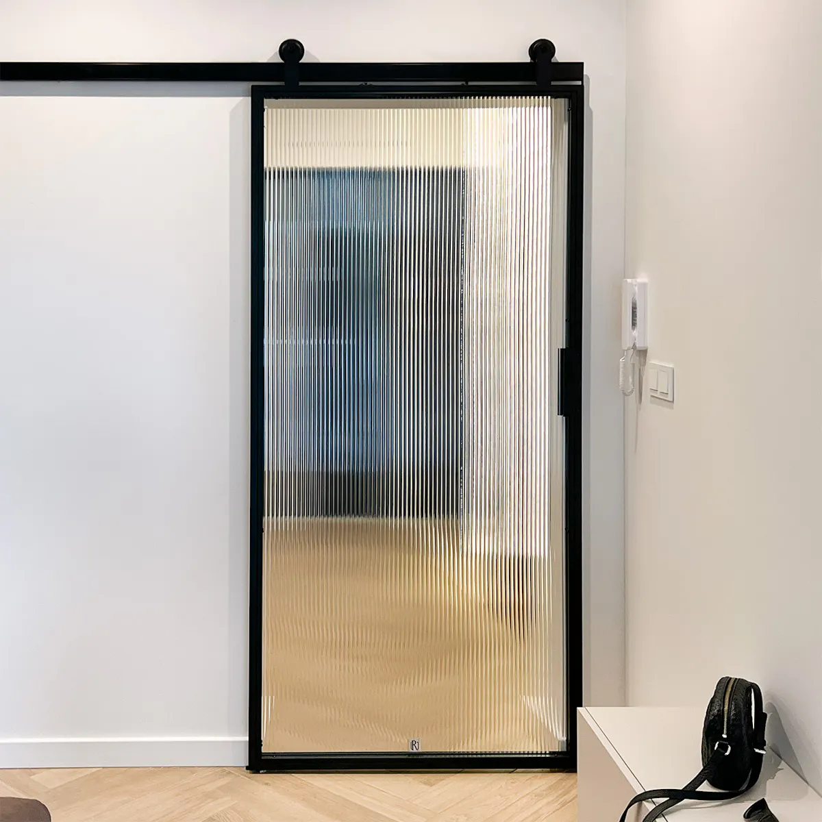 Sliding doors with fluted glass connecting the minimalist living room with the hallway.
