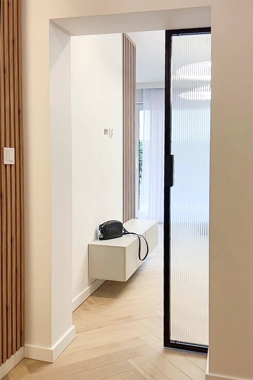 The passageway between the living room and the hallway features sliding doors with fluted glass.
