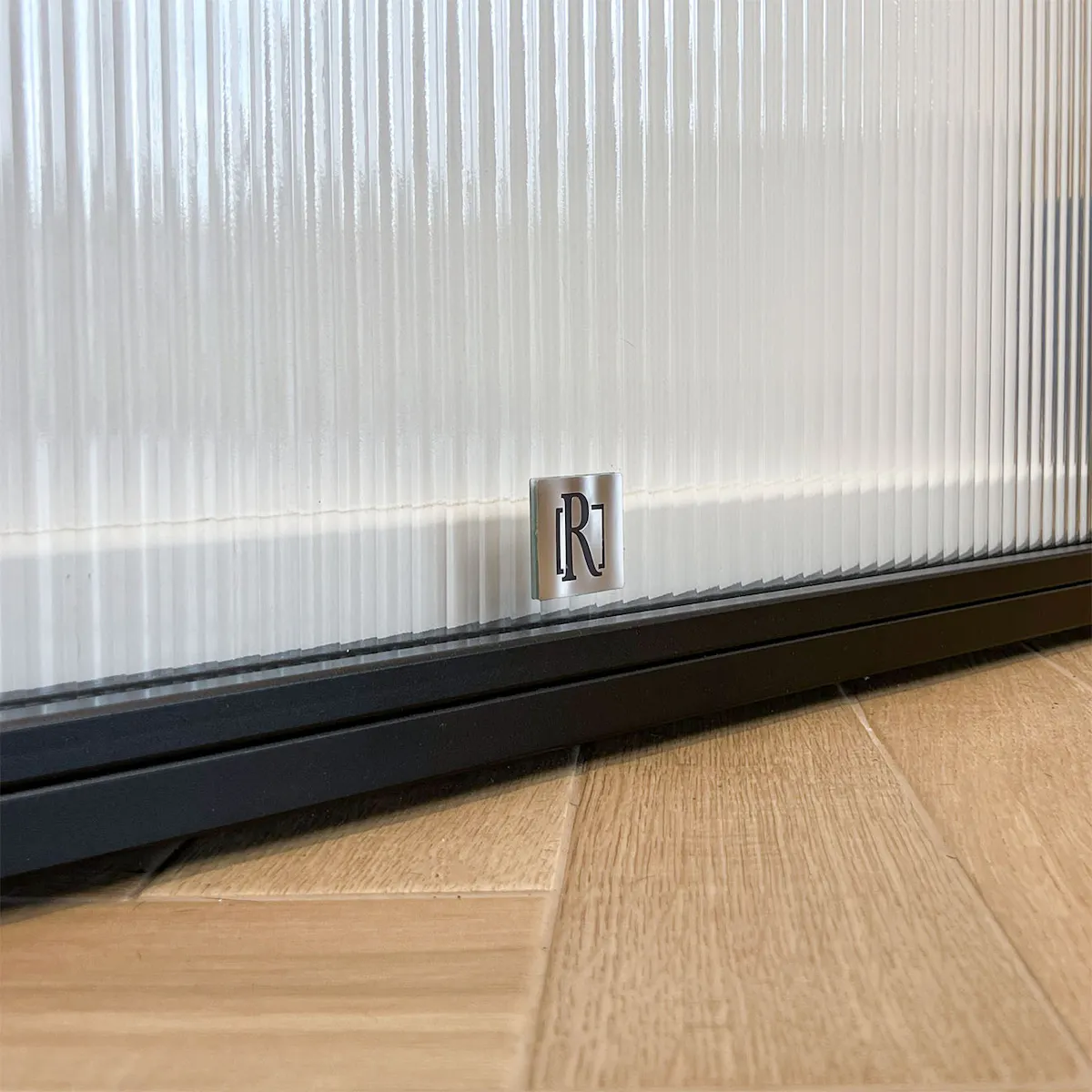 A close-up of the bottom edge of the Reno sliding door against a light-coloured herringbone floor.