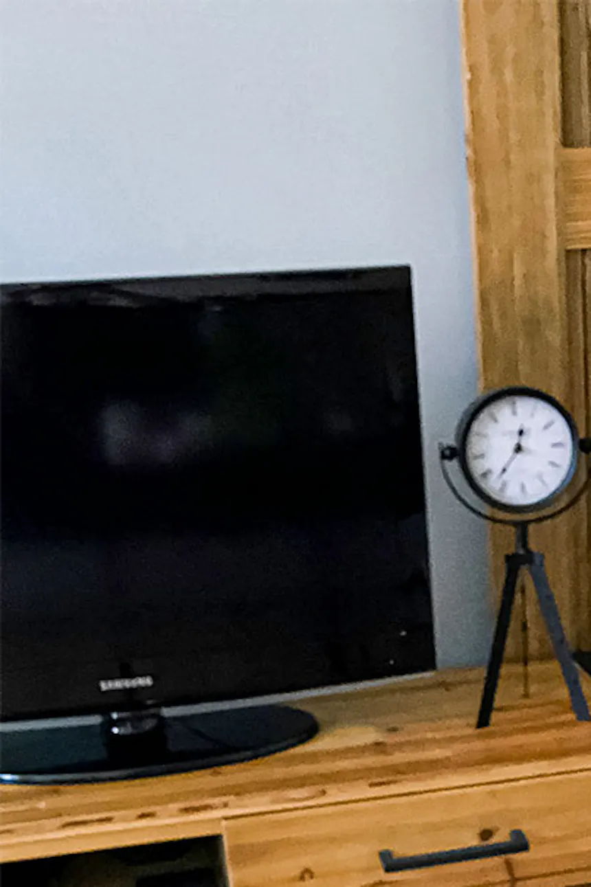 sliding doors in a small apartment, wooden sliding door with black handle, wooden TV cabinet, decorative metal clock on wooden cabinet