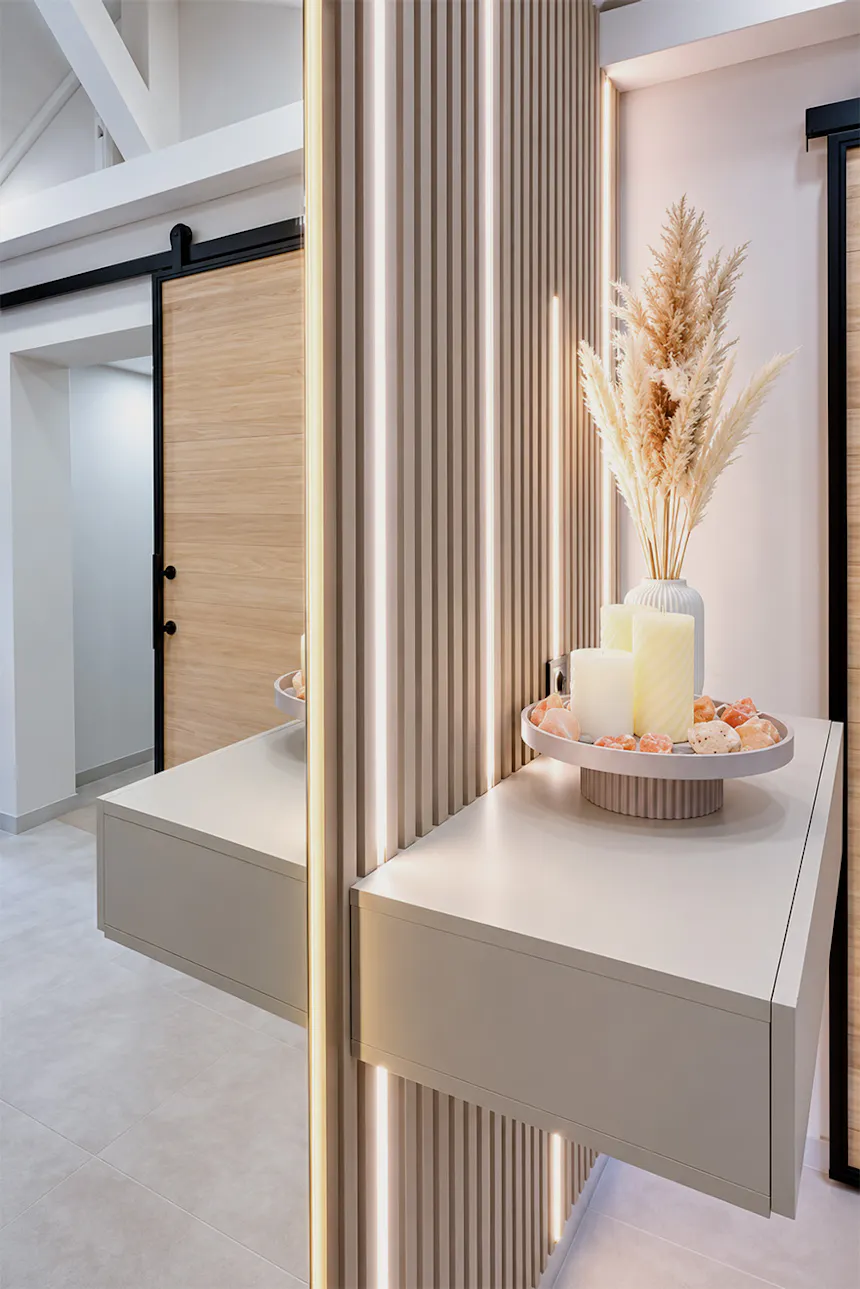 A modern, suspended console table with decorative candles on a tray, mounted on a slatted wall with LED lighting.