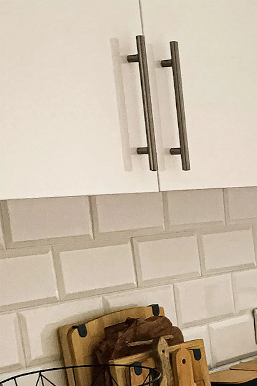 sliding doors in a small apartment, white kitchen cabinet with a wooden top, black kitchen accessories, white tiles on the kitchen wall