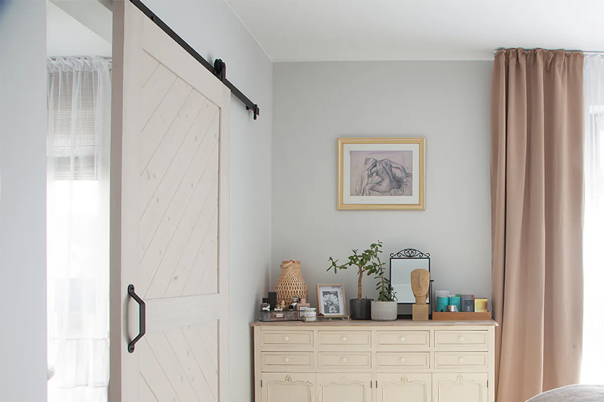 a bright and spacious bedroom with a bathroom hidden behind white sliding doors