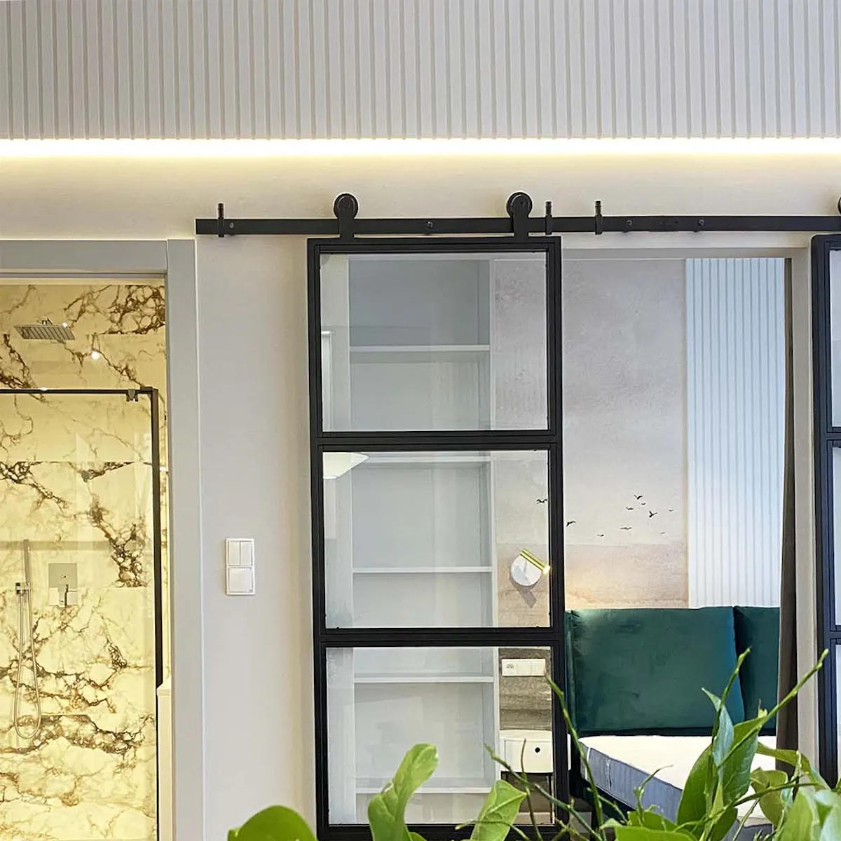 Double metal glass sliding doors separating living room from bedroom in modern apartment