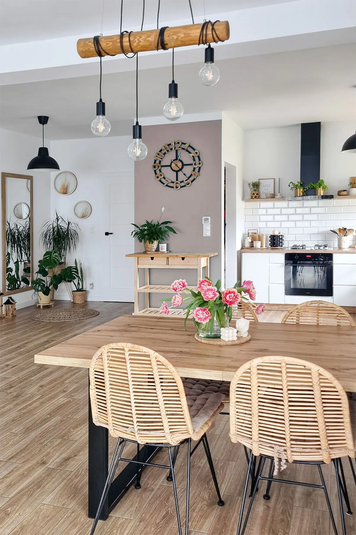 chaises ajourées dans une table avec un plateau en bois dans une salle à manger ouverte combinée à une cuisine décorée dans un style scandinave