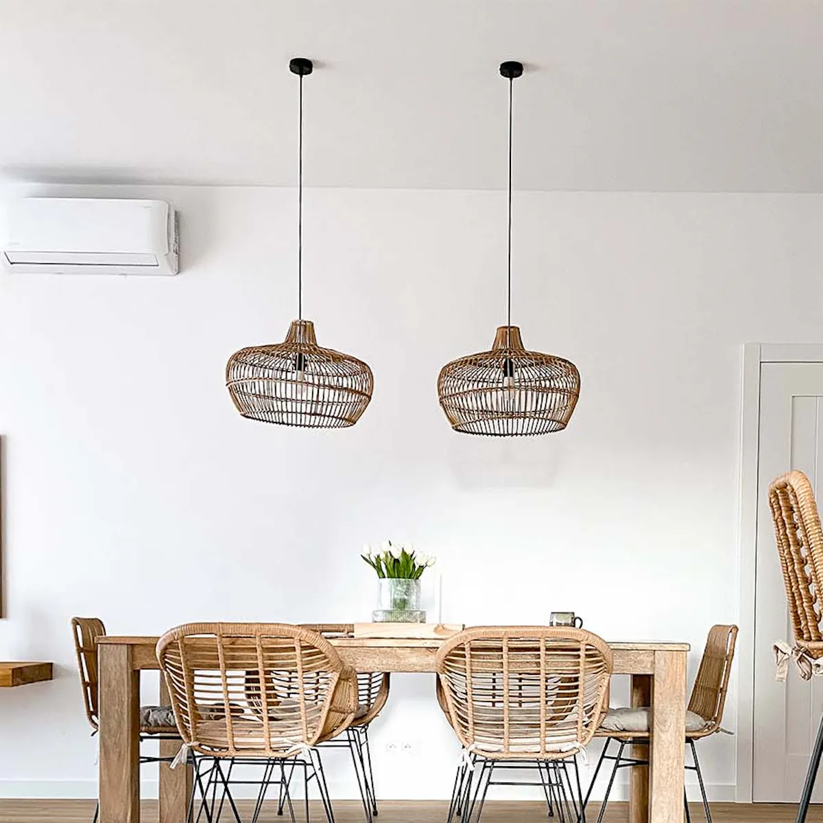 Rattan chairs on metal legs, rattan bar stools, and woven pendant lamps in a white-walled living room