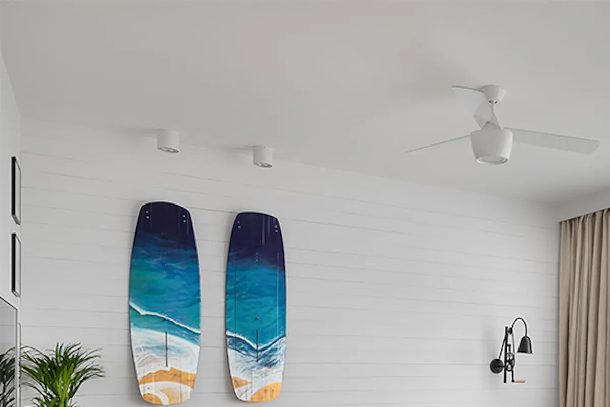 spacious living room with a California coastal style, a light brown sofa, a wooden coffee table, a blue decorative surfboard, white walls in the living room with a hardwood floor