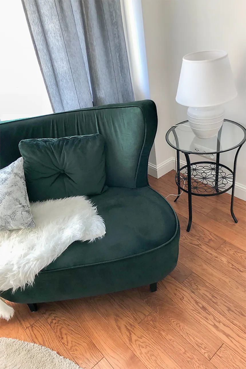 Green armchair, metal and glass table, living room, lamp on the table