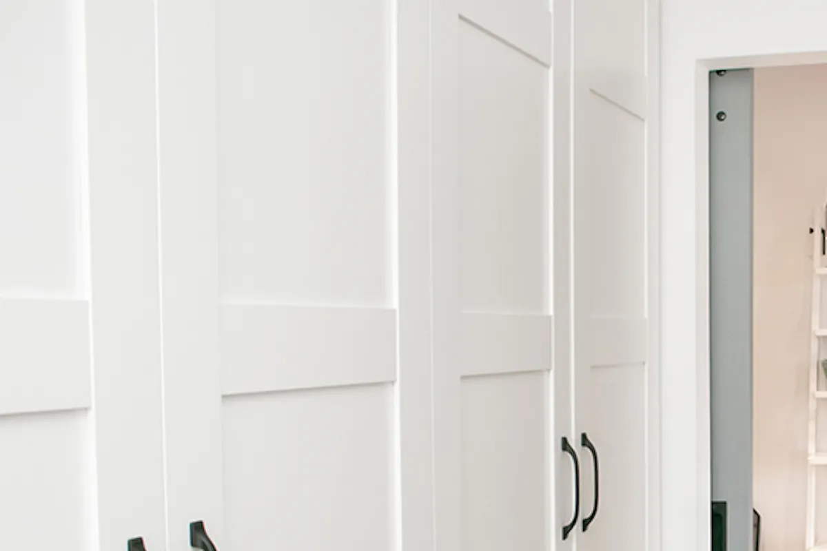 Sliding door in apartment building, wood sliding door, pantry sliding door, grey sliding door, white bookshelf in hallway.