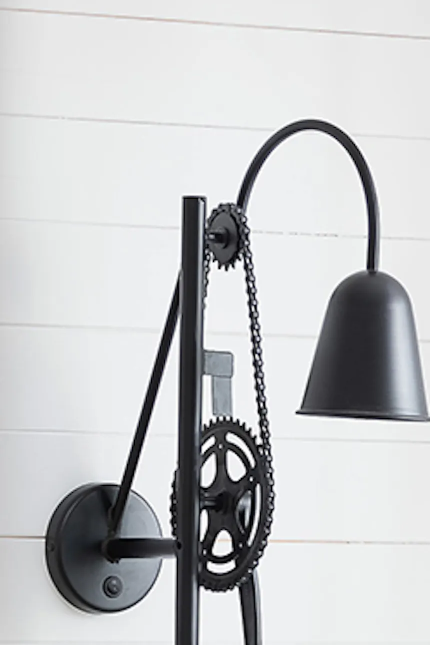 black industrial lamp on white wall, light brown sofa, decorative pillows