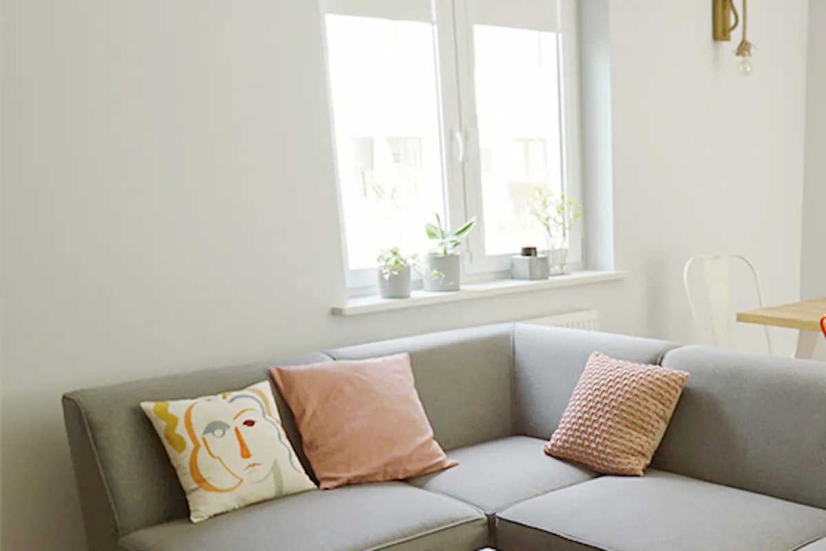 Large gray sofa, decorative pillows, metal-leg coffee table, colorful chairs in the dining room
