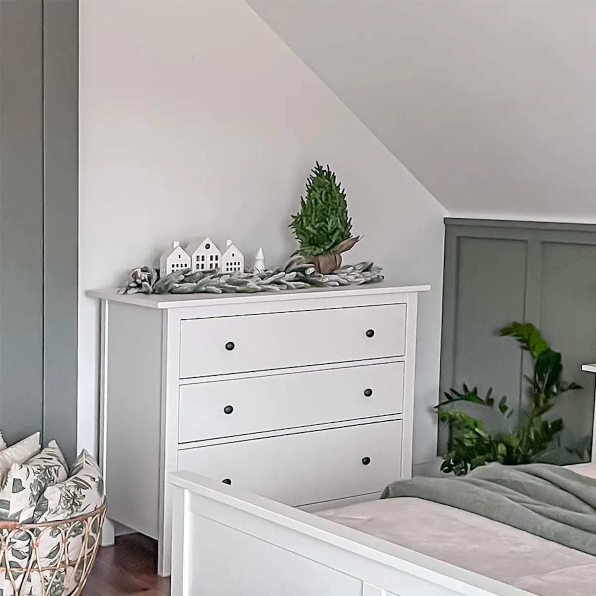 White bed and white dresser under a sloped ceiling in the bedroom