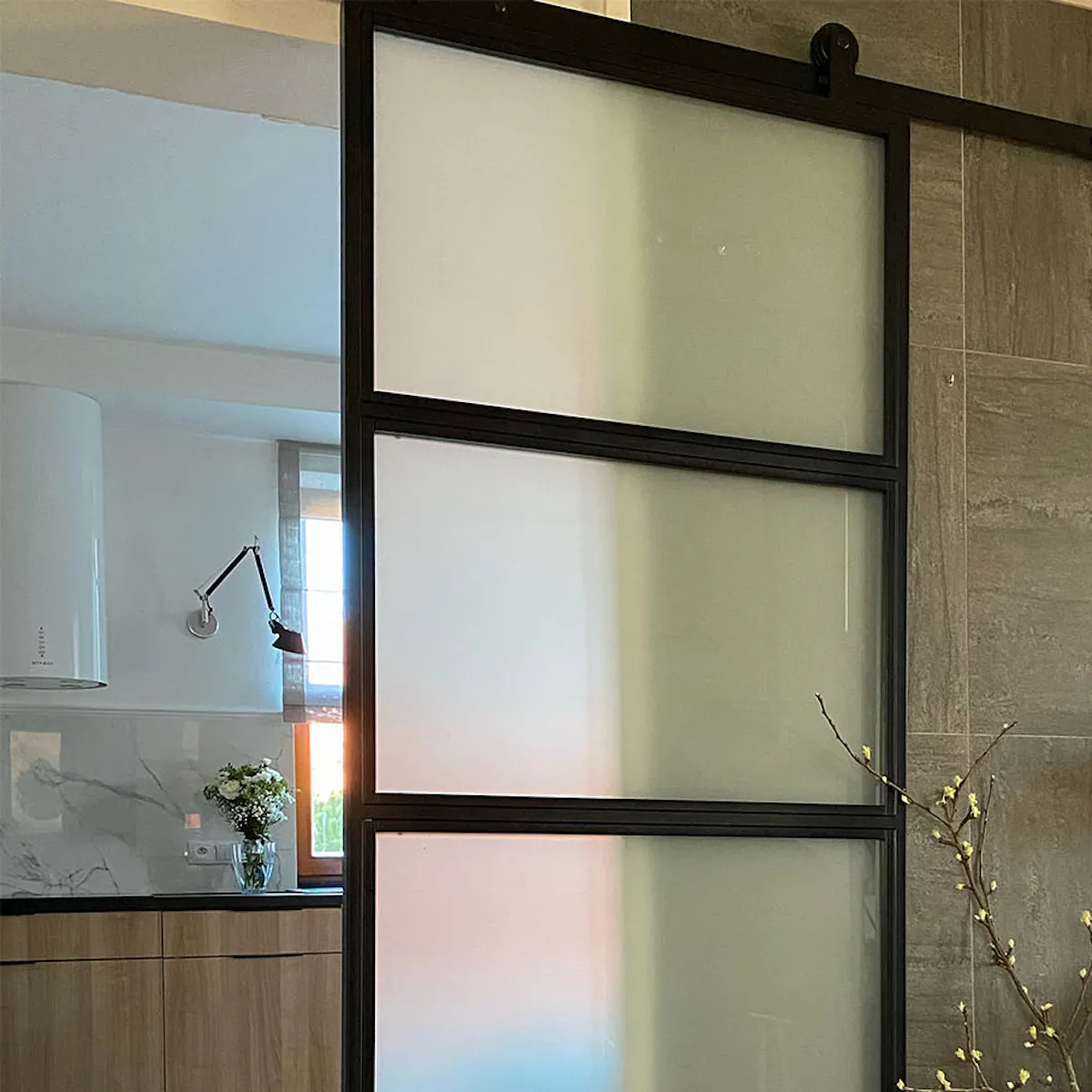 Loft glass doors, sliding door to kitchen, metal glass door between kitchen and entryway, golden lamp on black dresser, bright kitchen