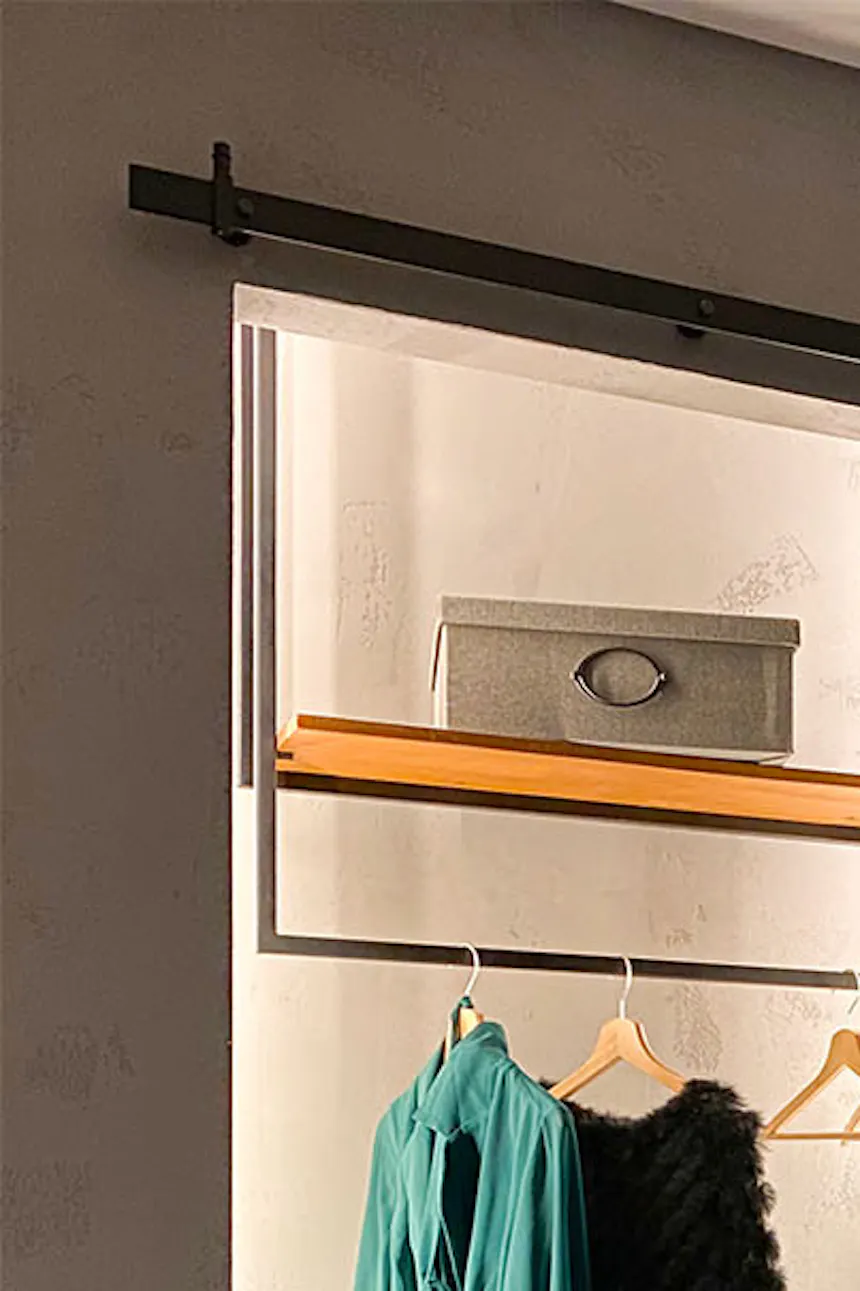 Open sliding doors revealing a small loft-style walk-in closet in a bedroom