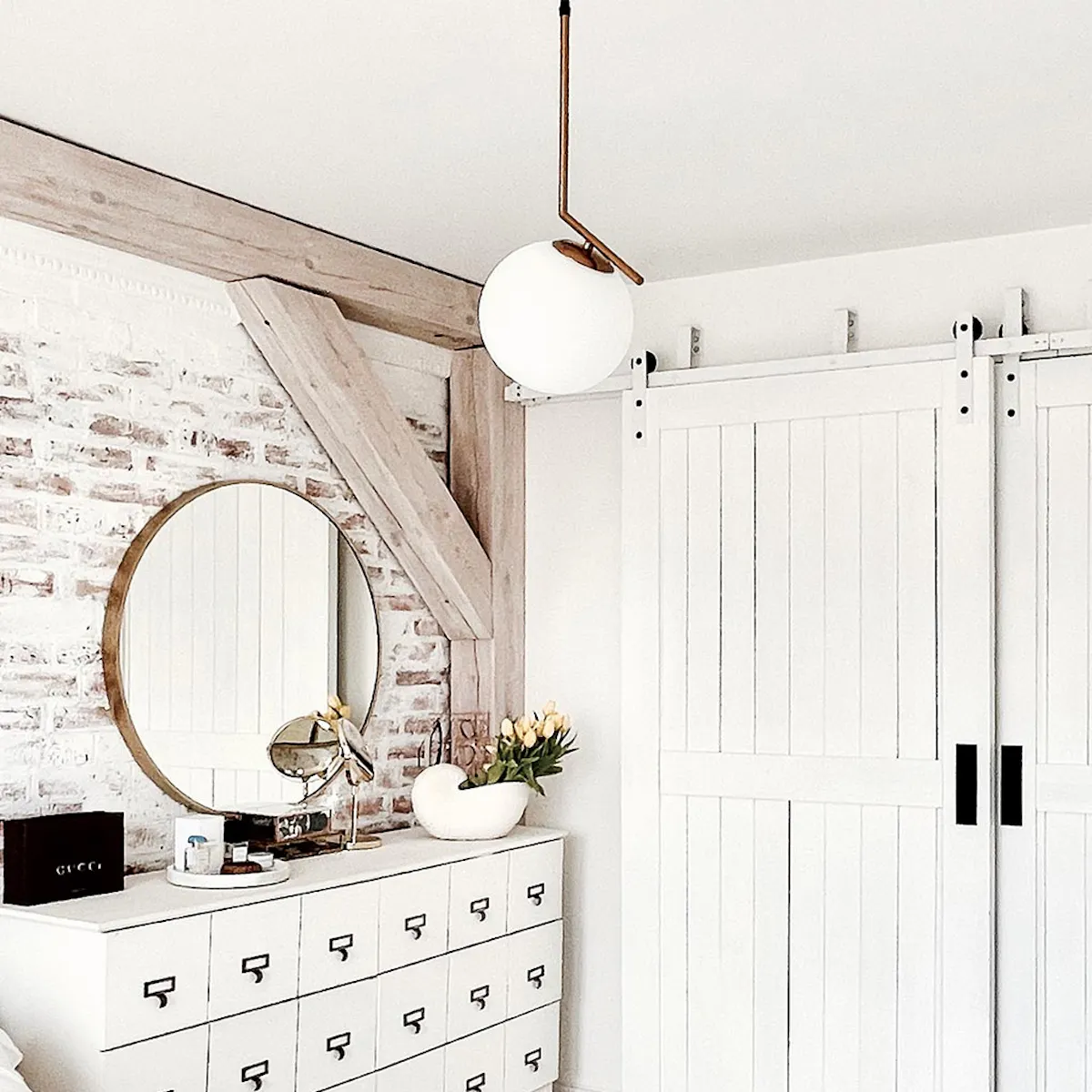 portes coulissantes blanches à deux vantaux dans une chambre à coucher avec une commode blanche et une brique au mur