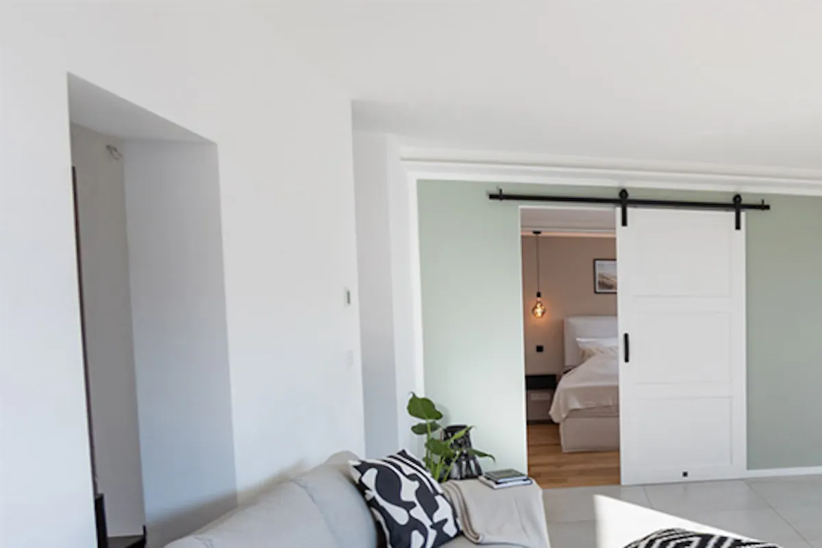Gray sofa, decorative pouf with geometric patterned pillows, long low TV stand, seating area in modern living room
