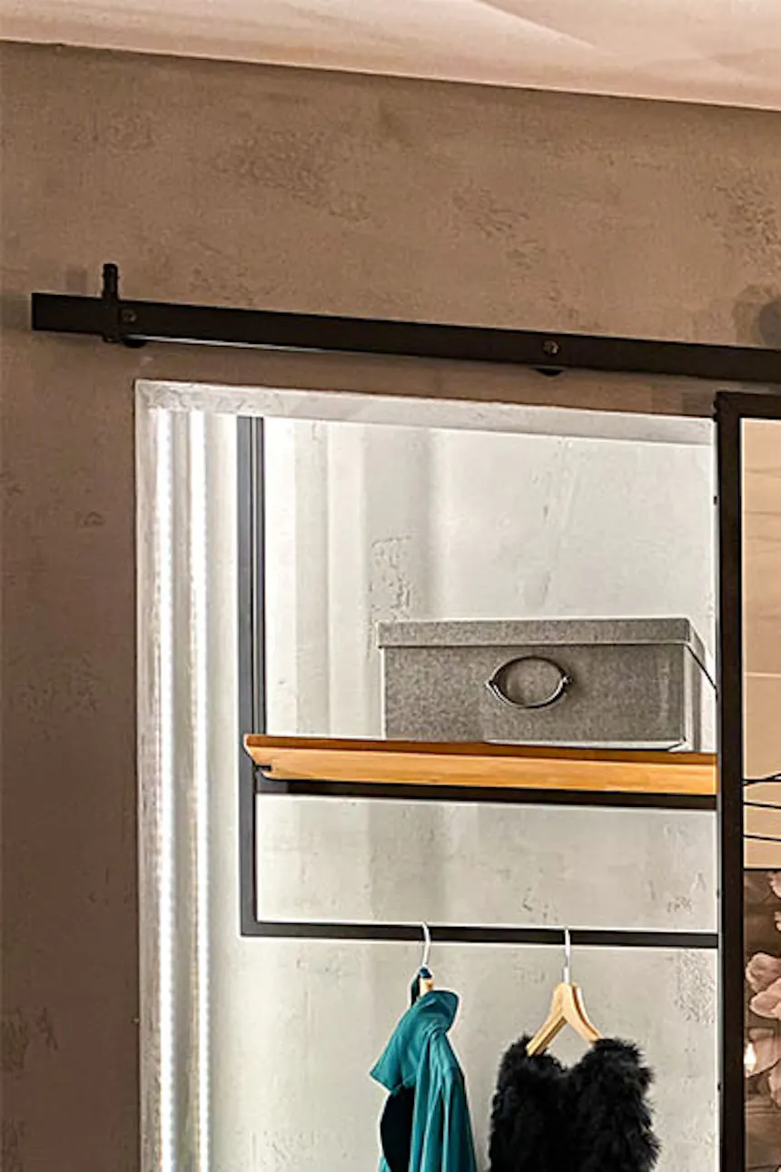 Open sliding doors revealing small dressing room in niche in gray-decorated bedroom