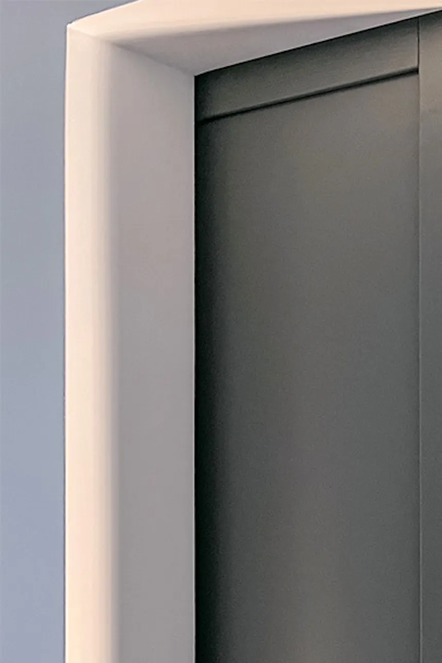 une porte ouverte montrant un fragment de chambre avec un lit et une coiffeuse