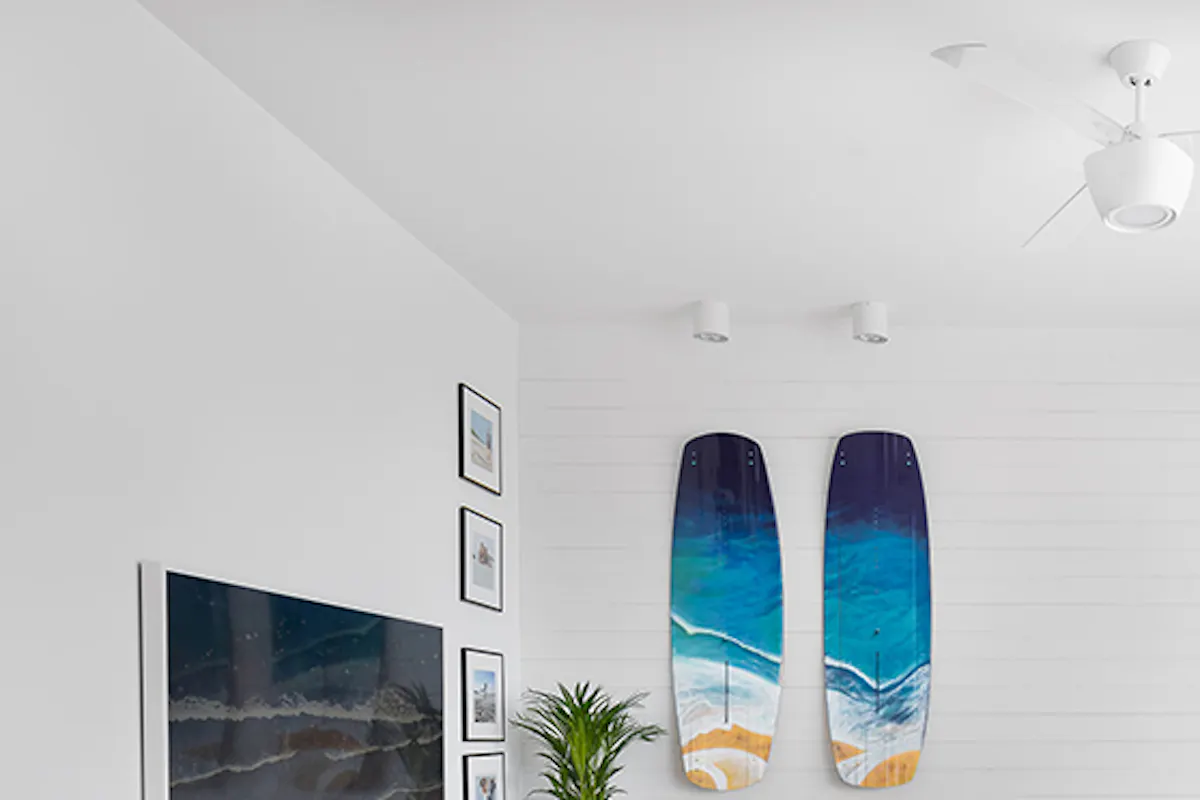 large and bright living room, white walls in the living room, blue decorative surfboard on the wall, wooden coffee table, large sofa