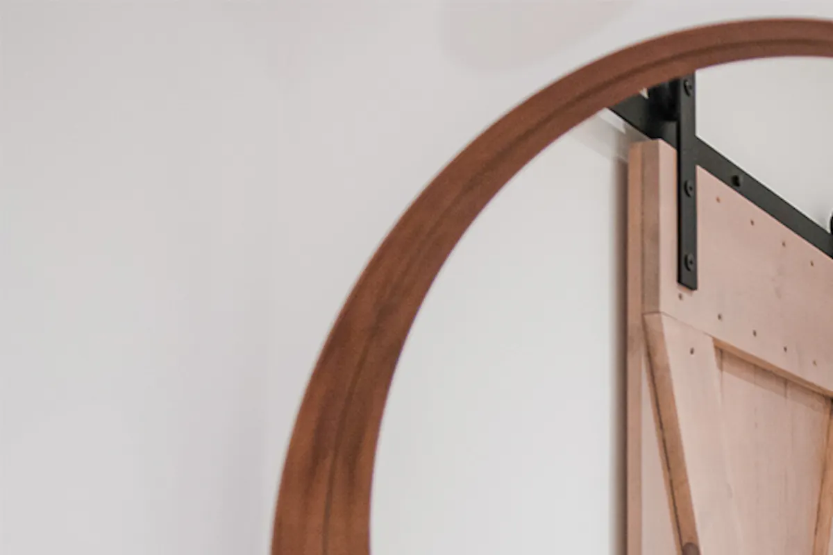 miroir rond dans un cadre en bois sur un mur blanc