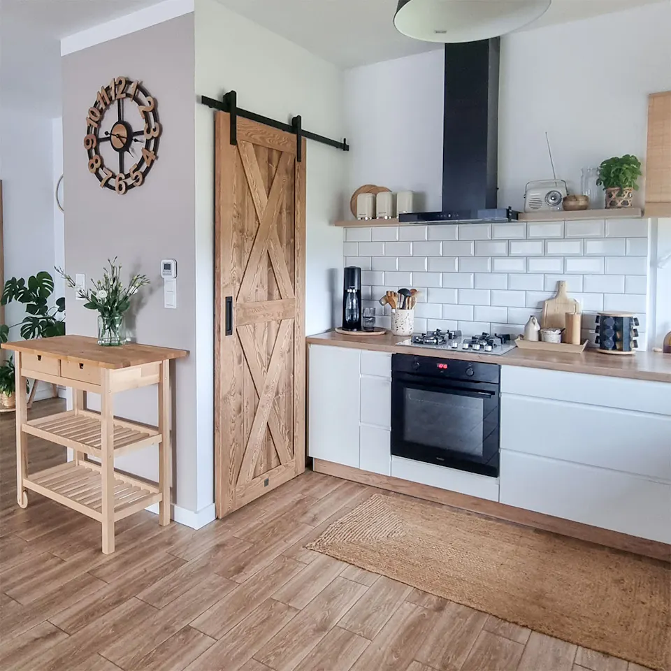 wooden sliding doors closing a pantry in a kitchen decorated in a Scandinavian style with white cabinets and wooden accessories