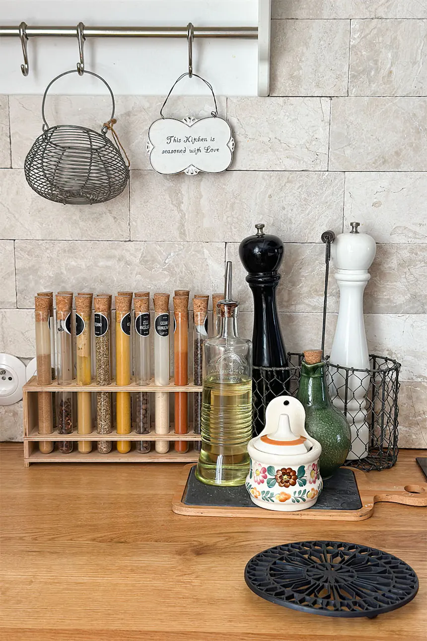 Spices in glass vials and a pepper mill on a wooden worktop in a cosy kitchen.